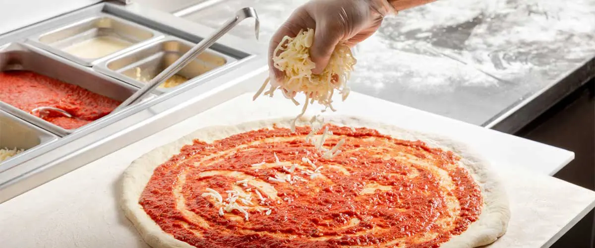 Pizza being made and topped with cheese